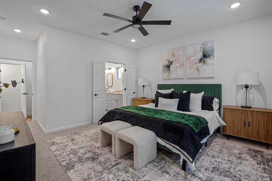 Bedroom with ensuite bathroom, ceiling fan, and light colored carpet