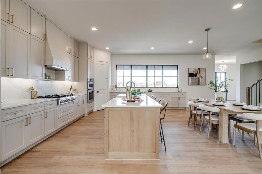 Kitchen with light wood finished floors, gas stovetop, light countertops, tasteful backsplash, and a center island