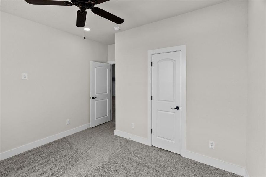 Unfurnished bedroom featuring ceiling fan and light colored carpet