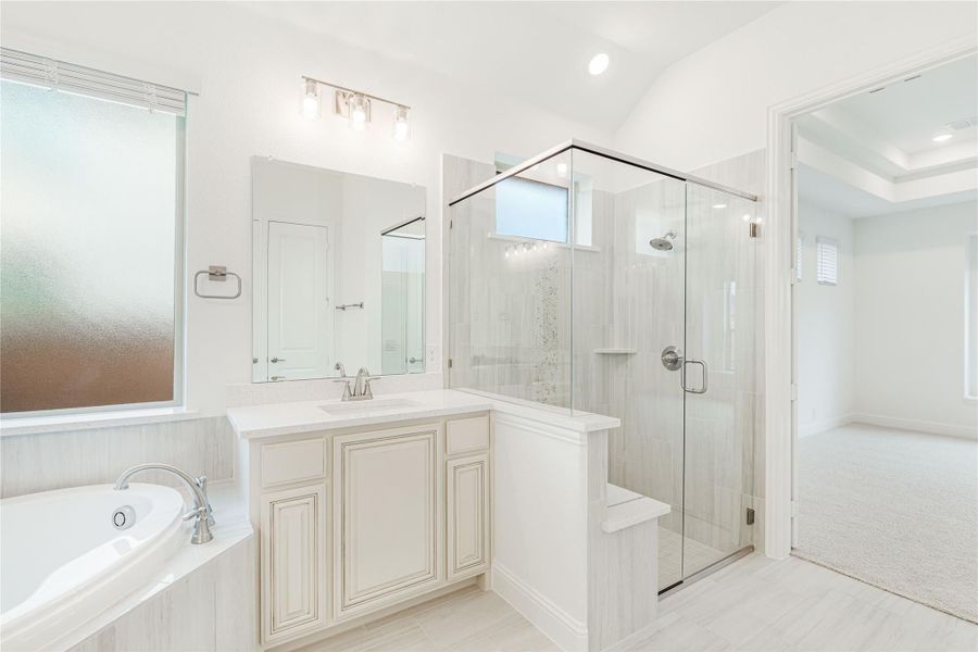 Master bathroom with glass walk-in shower, soaking tub, and white vanity cabinets
