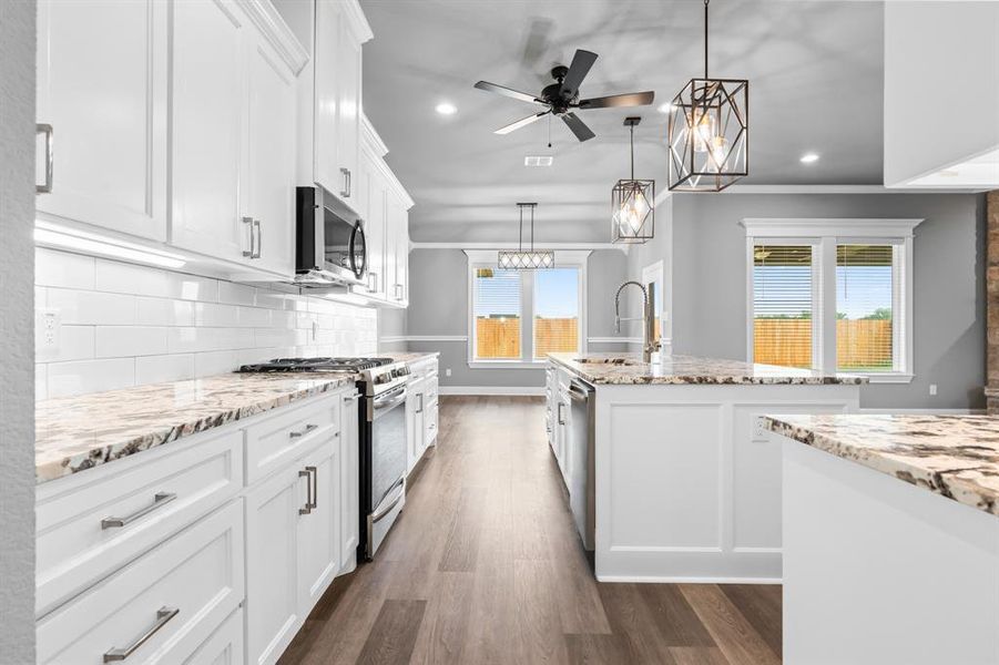 Kitchen with a wealth of natural light, stainless steel appliances, dark wood-style floors, and a sink Kitchen with a wealth of natural light, stainless steel appliances, dark wood-style floors, and a sink