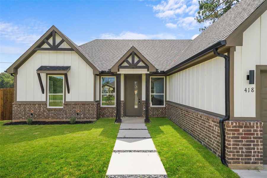Modern farmhouse exterior featuring vertical siding, dark brick skirting, and a gabled roofline