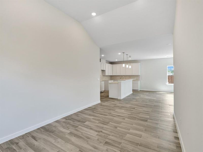 Unfurnished living room featuring lofted ceiling, light hardwood / wood-style floors, and sink