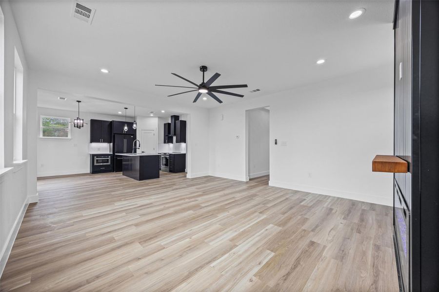 Open-concept living space with light wood-finish flooring, a contemporary ceiling fan, and recessed lighting Open-concept living space with light wood-finish flooring, a contemporary ceiling fan, and recessed lighting