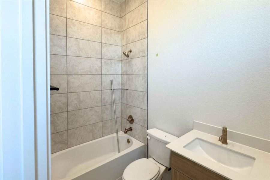 Bathroom featuring shower / tub combination, vanity, and a textured wall