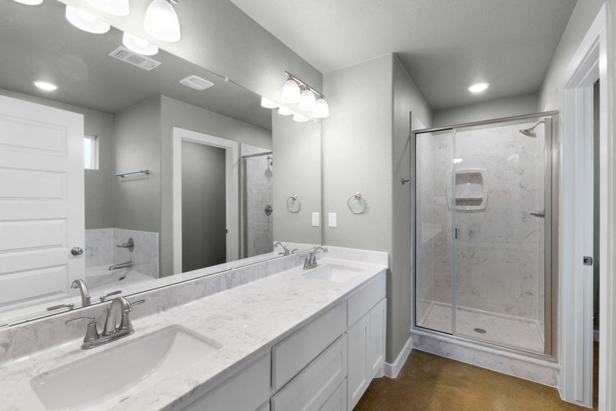 Double vanity with sleek countertops offers ample space in this modern bath.