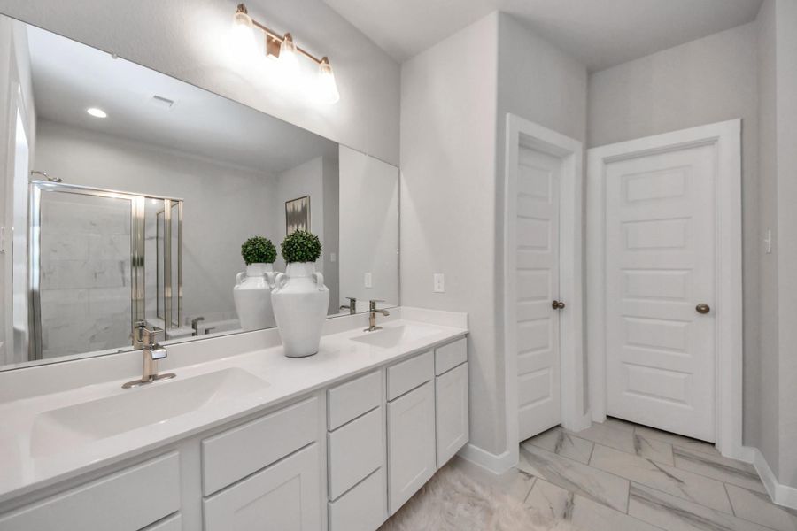 Elevate your daily routine at the elegant vanity, now equipped with double sinks, light countertops, modern hardware, and beautiful vanity lights. Sample photo of completed home with similar floor plan. Actual colors and selections may vary.