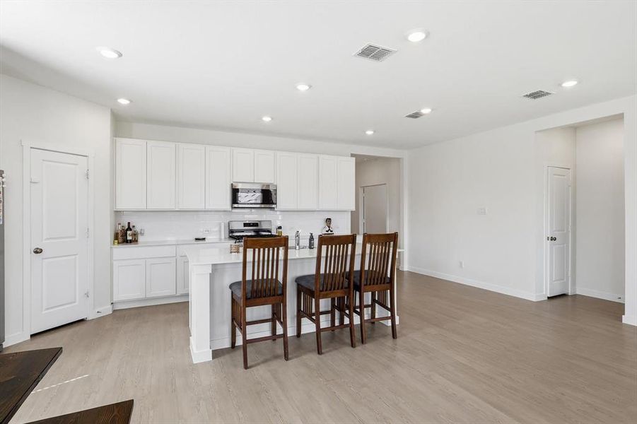 Open-concept kitchen and living area featuring wood-finish flooring Open-concept kitchen and living area featuring wood-finish flooring