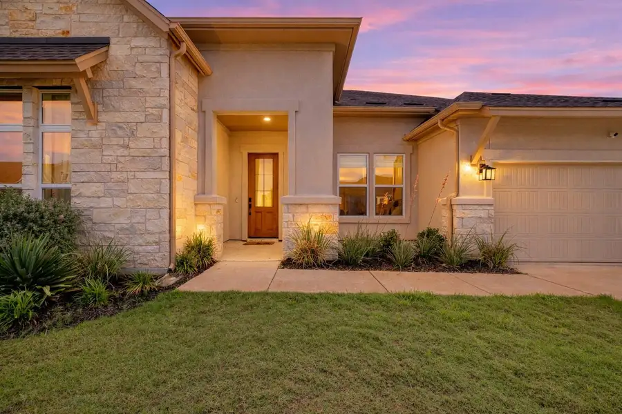 The property features a stone and stucco exterior, a well-maintained lawn, and a concrete driveway