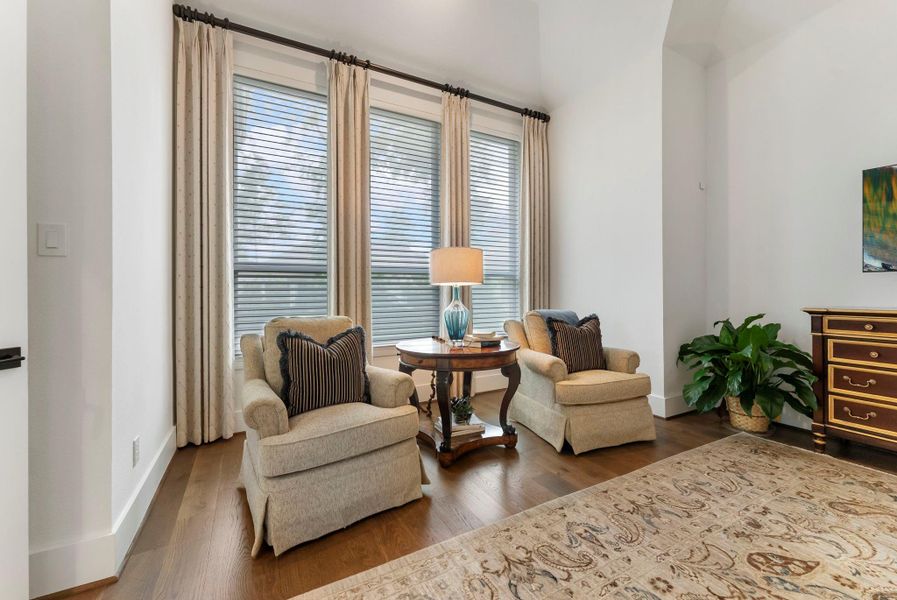 A sitting area within the primary suite adds flexibility for reading, relaxing, or creating a quiet morning space. Custom curtains and carefully planned windows help reduce harsh western light while keeping the room inviting.