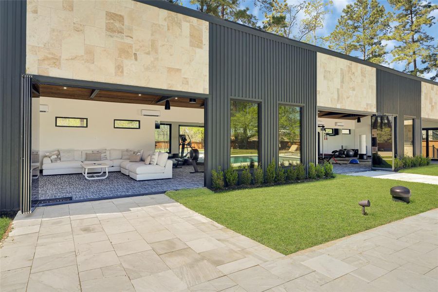 Modern home with a stylish exterior featuring a blend of stone and sleek paneling. The open-plan interior includes a spacious living area with large windows, offering views of the lush green lawn and an adjacent outdoor space. Perfect for those who appreciate contemporary design and seamless indoor-outdoor living.