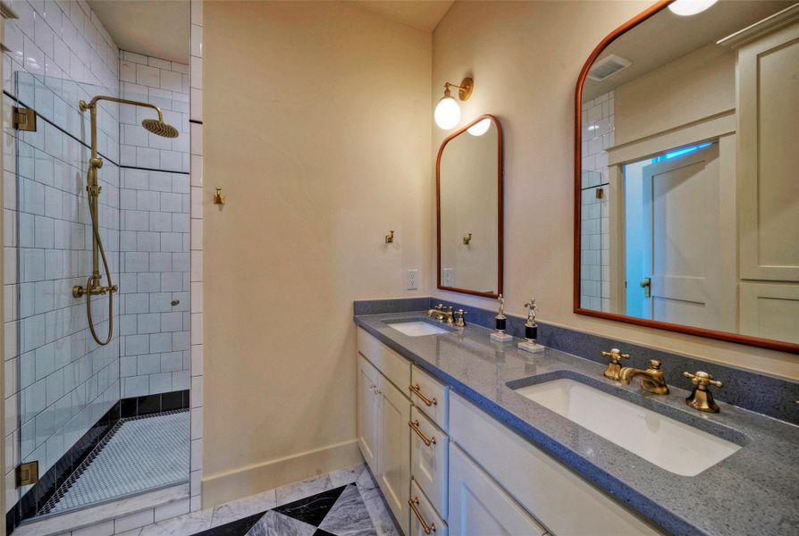 Double vanities with sleek countertops and a spacious walk-in shower elevate this bathroom's design.