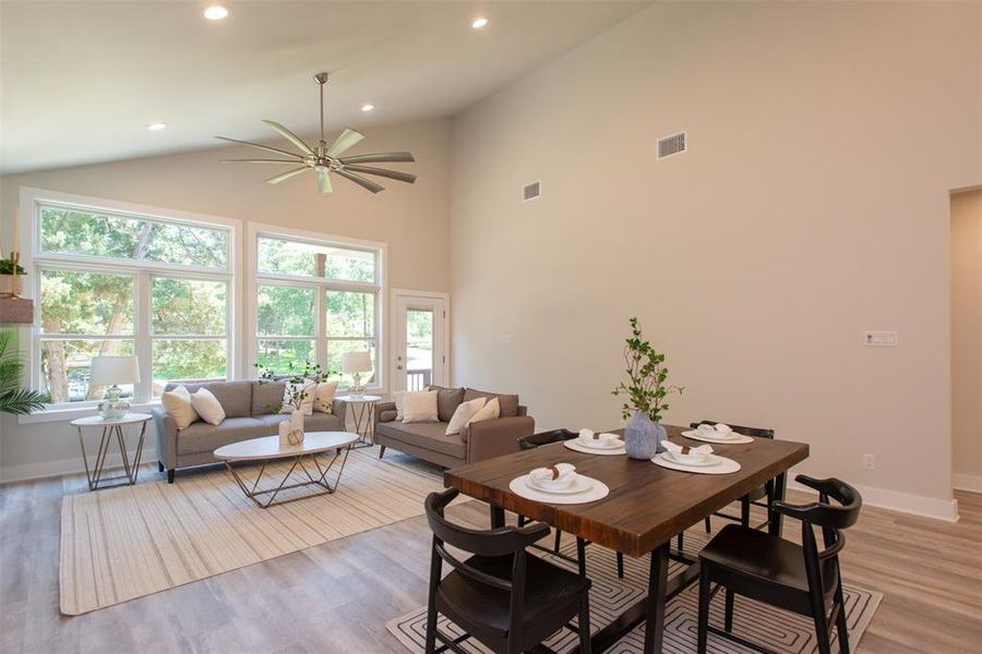 Dining space with light hardwood / wood-style floors, ceiling fan, and high vaulted ceiling