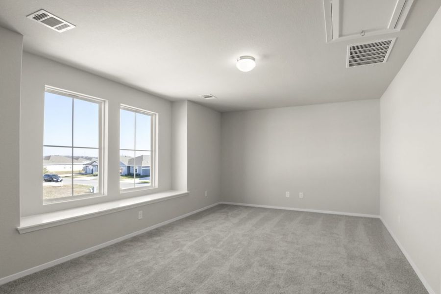 Image of a upstairs flex space with cream walls, tan carpeting and a two large windows with a bay area