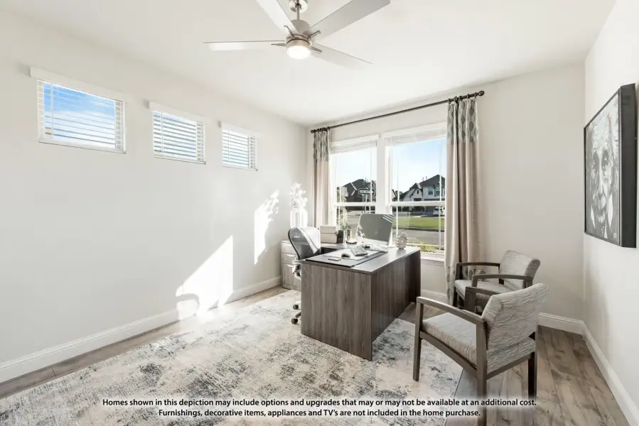 Home office with dark wood desk, ceiling fan, hardwood floors, and large window with neighborhood view