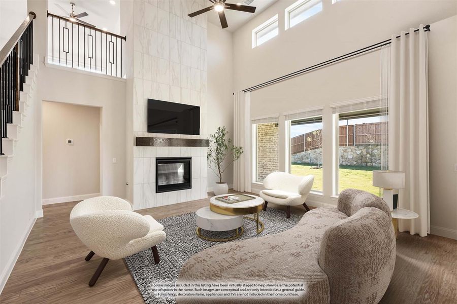 Living room with two-story ceiling, tile fireplace, ceiling fan, and hardwood floors open to staircase balcony Living room with two-story ceiling, tile fireplace, ceiling fan, and hardwood floors open to staircase balcony