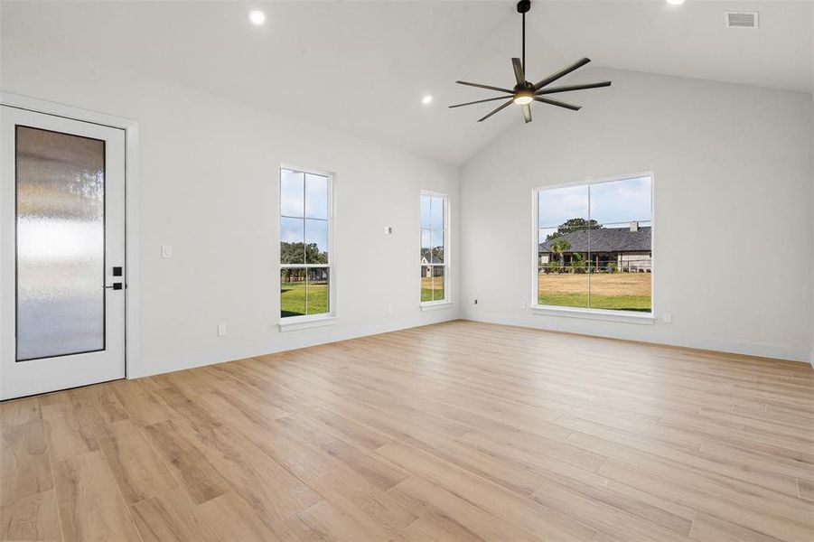 Unfurnished living room featuring light wood finished floors, recessed lighting, vaulted ceiling, and a ceiling fan Unfurnished living room featuring light wood finished floors, recessed lighting, vaulted ceiling, and a ceiling fan