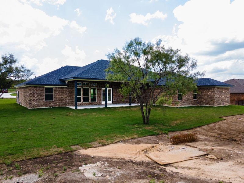 Rear view of property featuring a lawn, a patio, brick veneer, and a shingled roof Rear view of property featuring a lawn, a patio, brick veneer, and a shingled roof