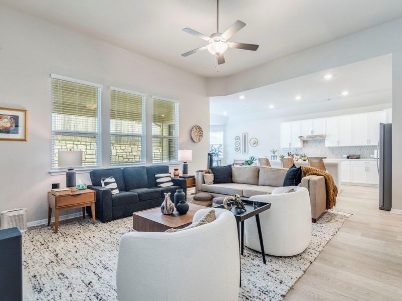 An inviting open-concept living space features light wood flooring and a kitchen with white cabinetry.