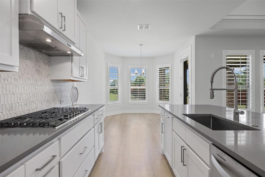 A well-appointed kitchen flows into a naturally illuminated dining area with bay windows.
