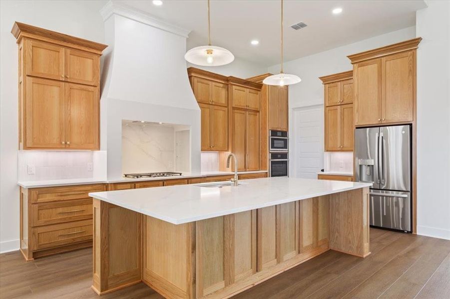 Kitchen featuring appliances with stainless steel finishes, pendant lighting, light stone countertops, decorative backsplash, and dark wood-style floors