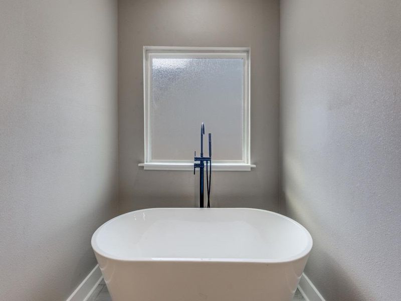 Bathroom with a textured wall and a freestanding bath