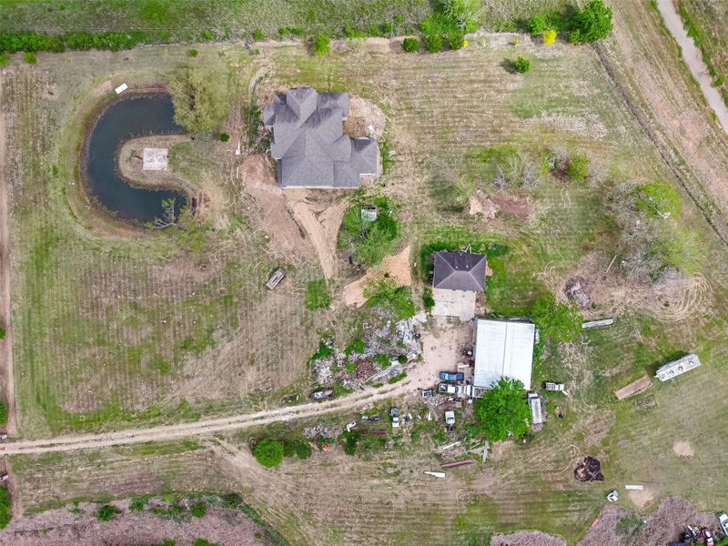 Aerial view of the property showcasing multiple structures, pond, and expansive grounds.