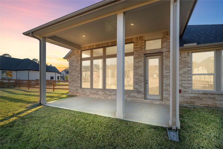 This expansive covered patio provides a fantastic outdoor living space, perfect for relaxing or entertaining year-round. The generous concrete area is supported by sturdy columns, and a wall of large windows and glass doors creates a seamless indoor-outdoor connection. This expansive covered patio provides a fantastic outdoor living space, perfect for relaxing or entertaining year-round. The generous concrete area is supported by sturdy columns, and a wall of large windows and glass doors creates a seamless indoor-outdoor connection.