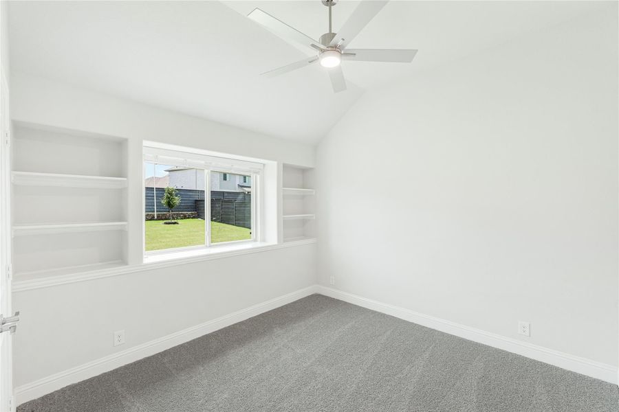 Empty bedroom with vaulted ceiling, ceiling fan, built-in shelves, and gray carpet Empty bedroom with vaulted ceiling, ceiling fan, built-in shelves, and gray carpet
