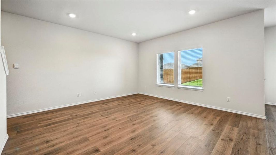 Open room featuring wood-finish flooring, recessed lighting, and white baseboards