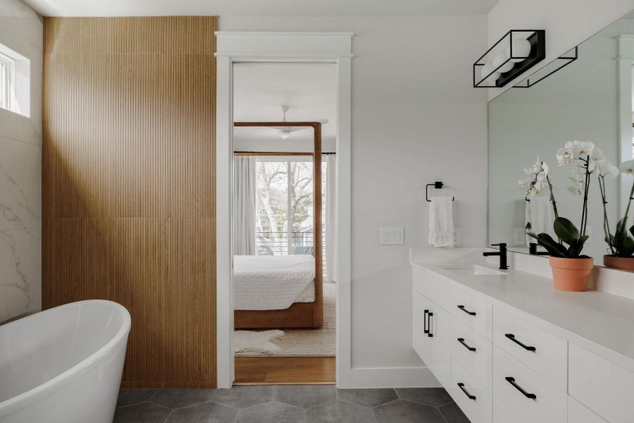 Full bathroom with ensuite bath, vanity, a soaking tub, and dark tile patterned flooring