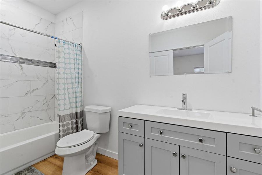 Bathroom with light wood finished floors, shower / tub combo with curtain, and vanity Bathroom with light wood finished floors, shower / tub combo with curtain, and vanity