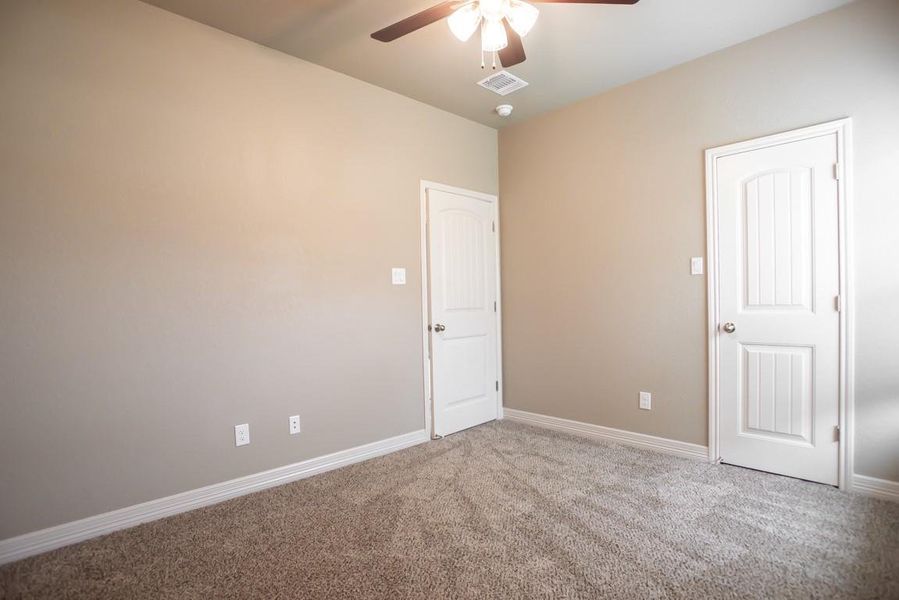 Carpeted empty room featuring ceiling fan and baseboards Carpeted empty room featuring ceiling fan and baseboards