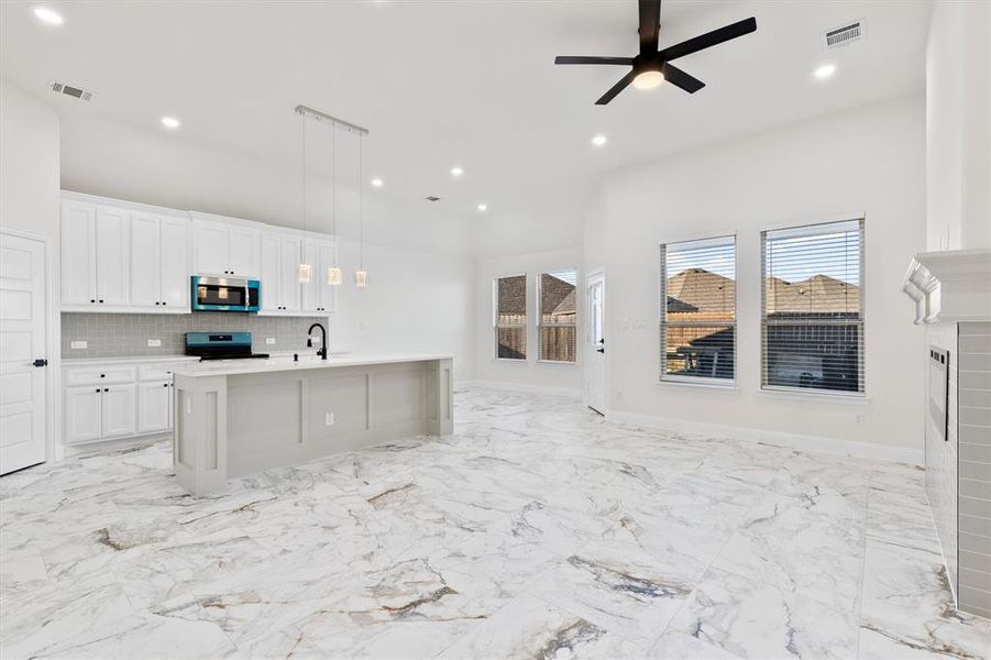 Kitchen with stainless steel appliances, visible vents, white cabinetry, open floor plan, and tasteful backsplash Kitchen with stainless steel appliances, visible vents, white cabinetry, open floor plan, and tasteful backsplash