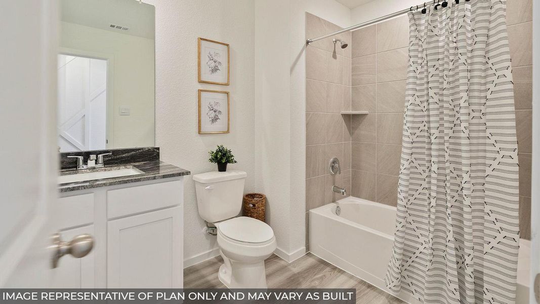 Full bathroom featuring a white vanity with dark granite countertop, a white toilet, and a tiled shower-tub combination with a built-in shelf