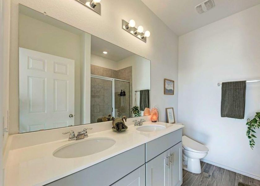 Full bathroom with double vanity, a shower stall, and wood finish floors Full bathroom with double vanity, a shower stall, and wood finish floors