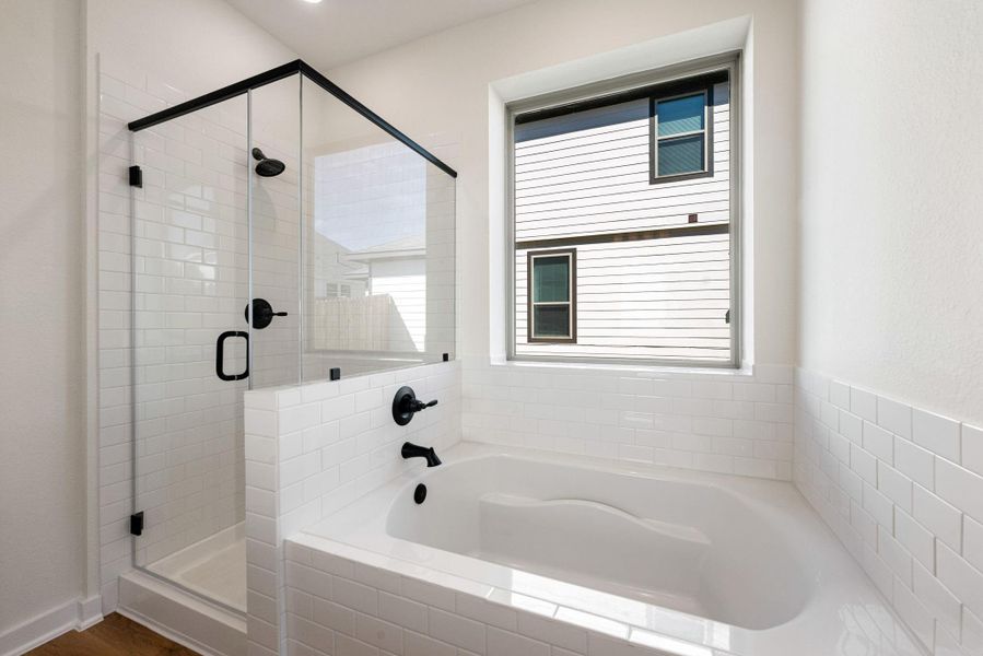 Additionally, the primary bathroom offers a serene space designed for relaxation. Featuring a deep, built-in soaking tube which sits beneath a large window, creating an ideal sport for unwinding. The dark framed walk-in shower with white tile surround and matte black finishes offers a luxurious bathing experience. Additionally, the primary bathroom offers a serene space designed for relaxation. Featuring a deep, built-in soaking tube which sits beneath a large window, creating an ideal sport for unwinding. The dark framed walk-in shower with white tile surround and matte black finishes offers a luxurious bathing experience.