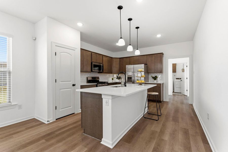 The open kitchen features quartz countertops, a large island with seating, stainless steel appliances, and ample cabinet space.