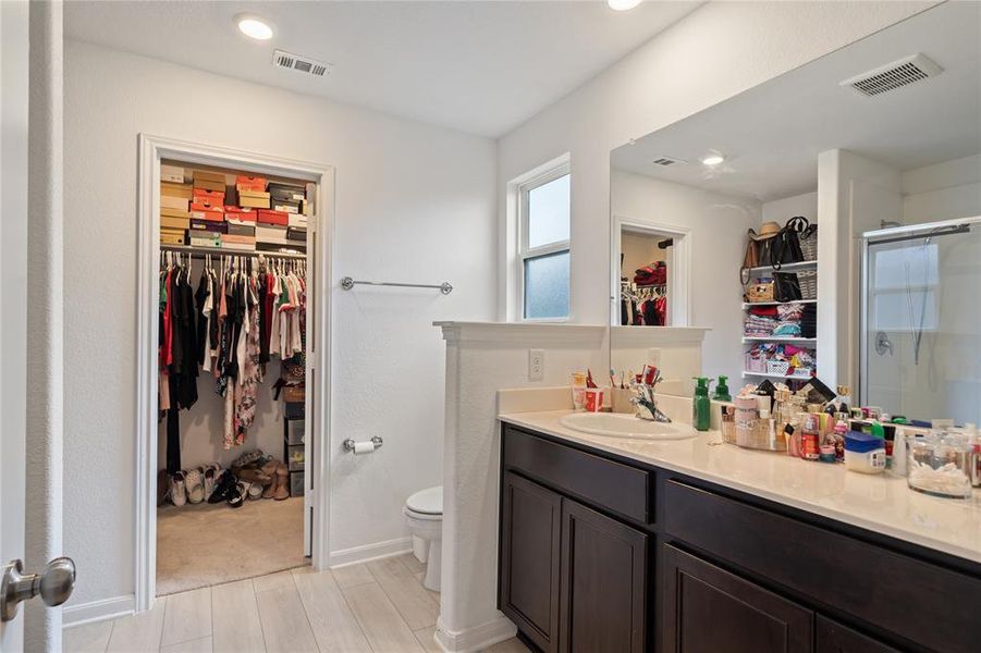 Bathroom featuring a spacious closet, vanity, a shower stall, light wood-style floors, and recessed lighting