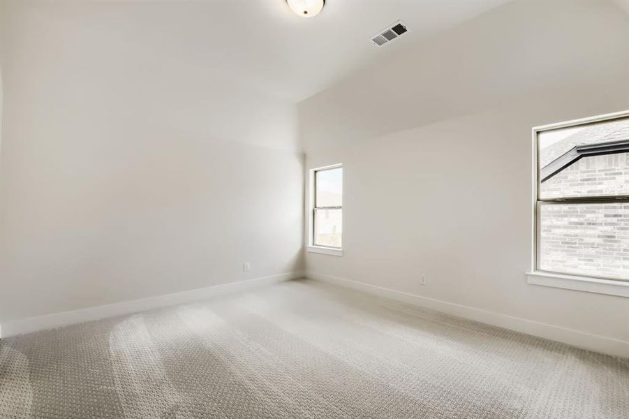 Neutral-toned room with vaulted ceilings and two large windows Neutral-toned room with vaulted ceilings and two large windows