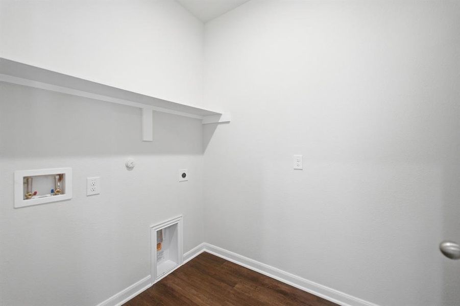Dedicated utility space featuring a wood-finish floor, white walls, and a built-in shelf