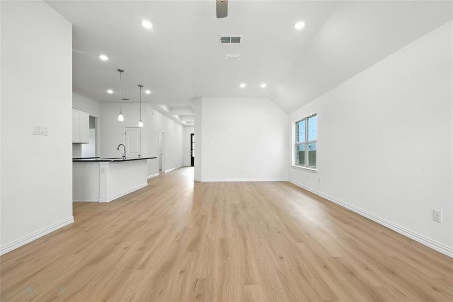 Unfurnished living room featuring recessed lighting, light wood finished floors, a ceiling fan, and lofted ceiling