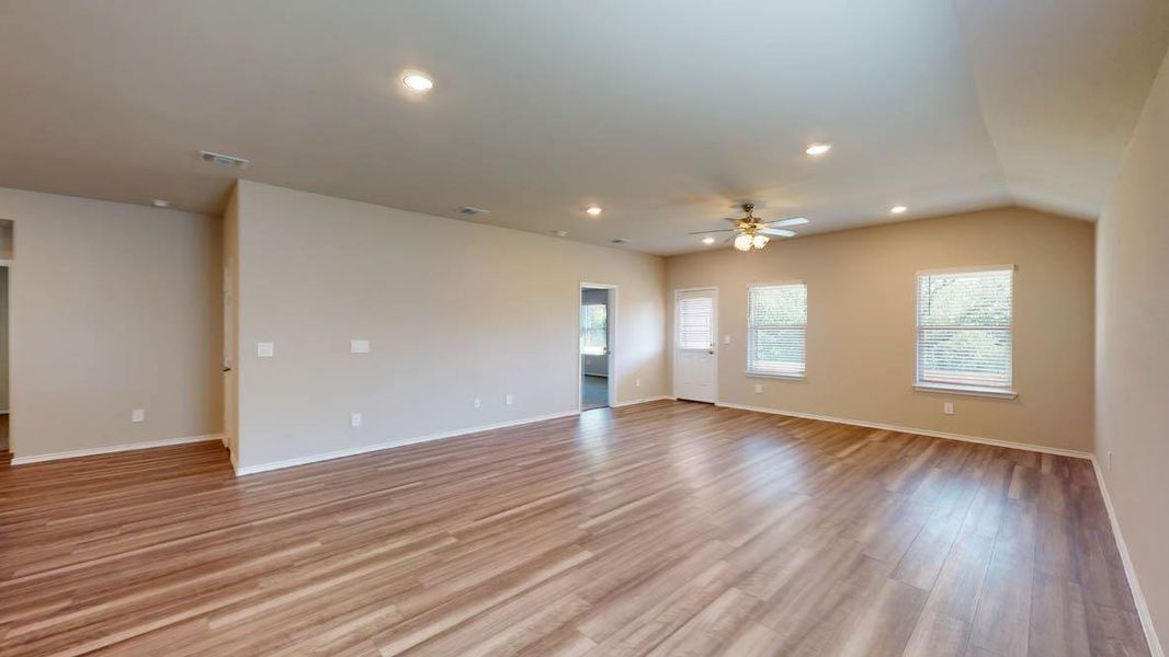 A spacious living area featuring warm wood flooring and abundant natural light.