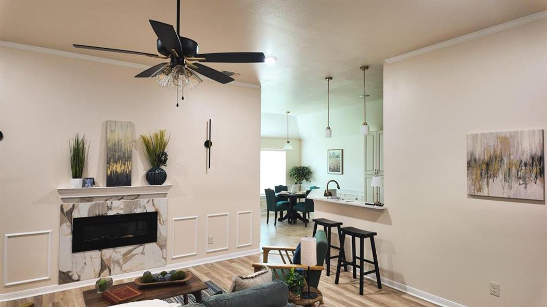 Living area featuring a fireplace with a stone-look surround, wood-finish flooring, and a ceiling fan