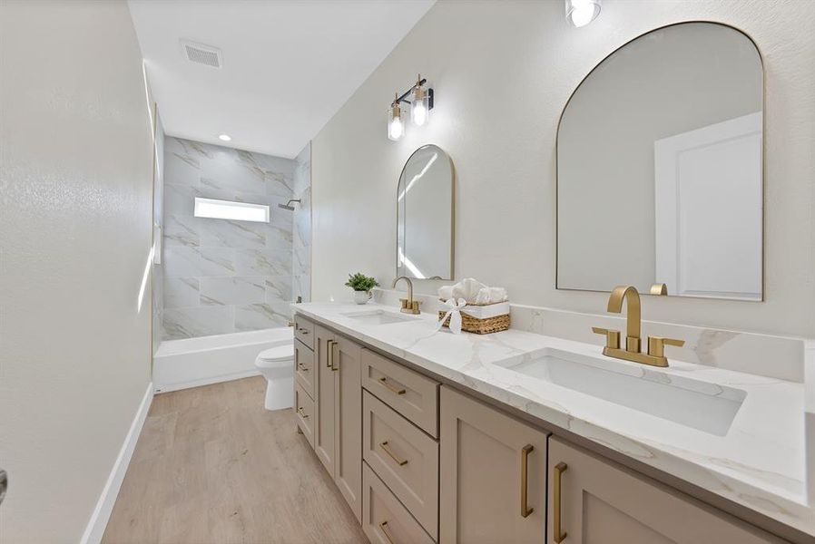 Bathroom featuring double vanity, shower / bath combination, and light wood-style floors