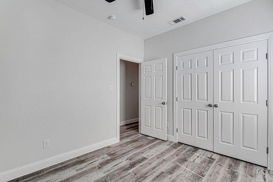 bedroom 2 with ceiling fan, wood-type flooring, and a closet