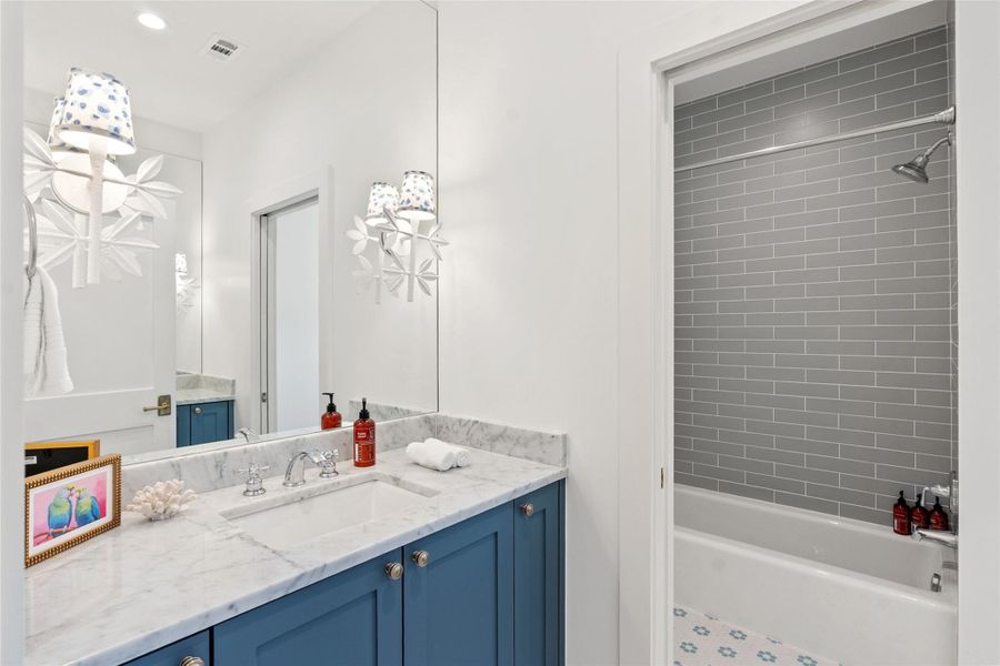Polished marble counters and blue cabinetry create a refreshing and elegant bathroom space. Polished marble counters and blue cabinetry create a refreshing and elegant bathroom space.