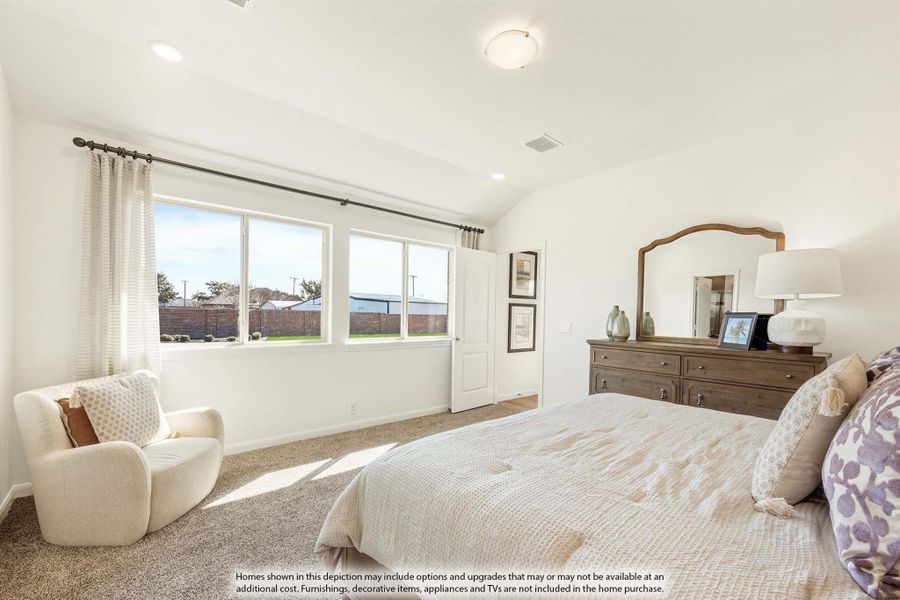 Bedroom with vaulted ceiling, carpet flooring, wood dresser, and large windows with backyard view