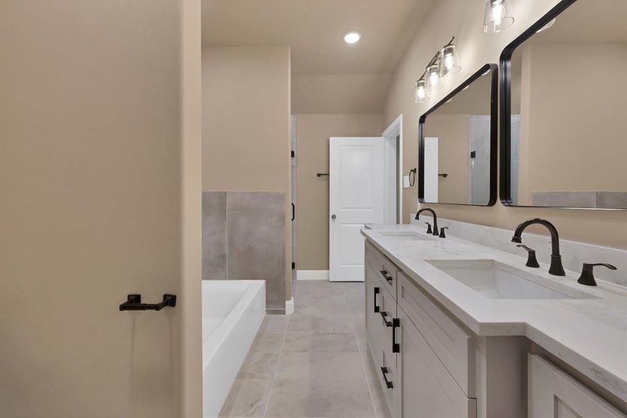 Full bath with double vanity, a garden tub, baseboards, and a sink Full bath with double vanity, a garden tub, baseboards, and a sink