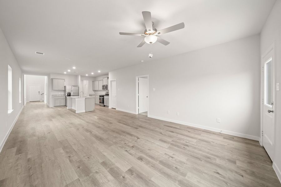 A large empty room with a ceiling fan and a wood floor.